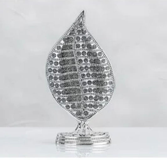 A silver-toned leaf-shaped decorative object with a textured, paved surface and a small matching base, shown against a light gray background.