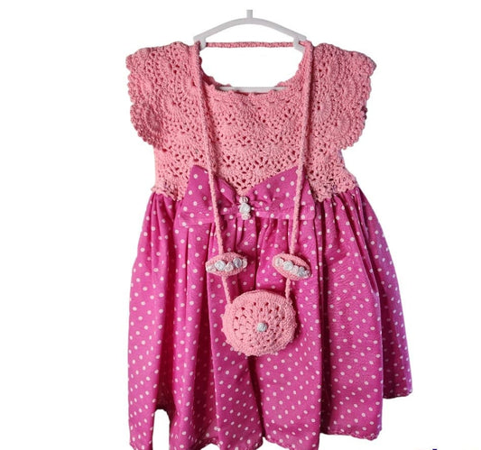 Pink dress with crochet top and polka dot skirt on a white background