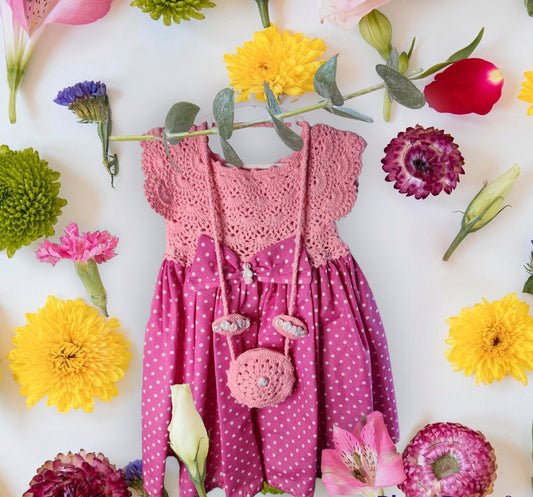 Pink crochet top and polka dot dress with matching bag surrounded by colorful flowers on a white background